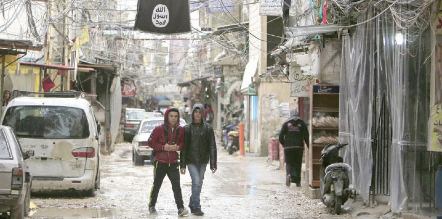 شباب صغار من مخيم عين الحلوة الفلسطيني في جنوب لبنان ويبدو علم داعش معلقا في الشارع  (رويترز)