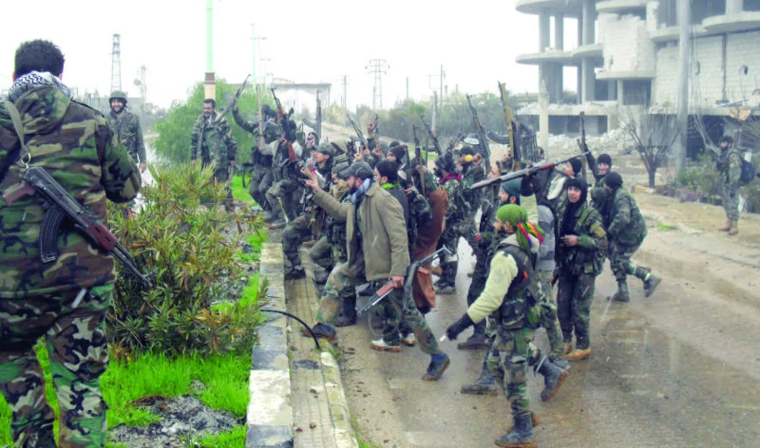 جماعة من قوات نظام الأسد تحتفل في أحد شوارع مدينة الشيخ مسكين في محافظة درعا بجنوب سوريا بسيطرتها على المدينة بدعم جوي من الطيران الحربي الروسي والميليشيات الشيعية الحليفة للنظام (أ.ف.ب)