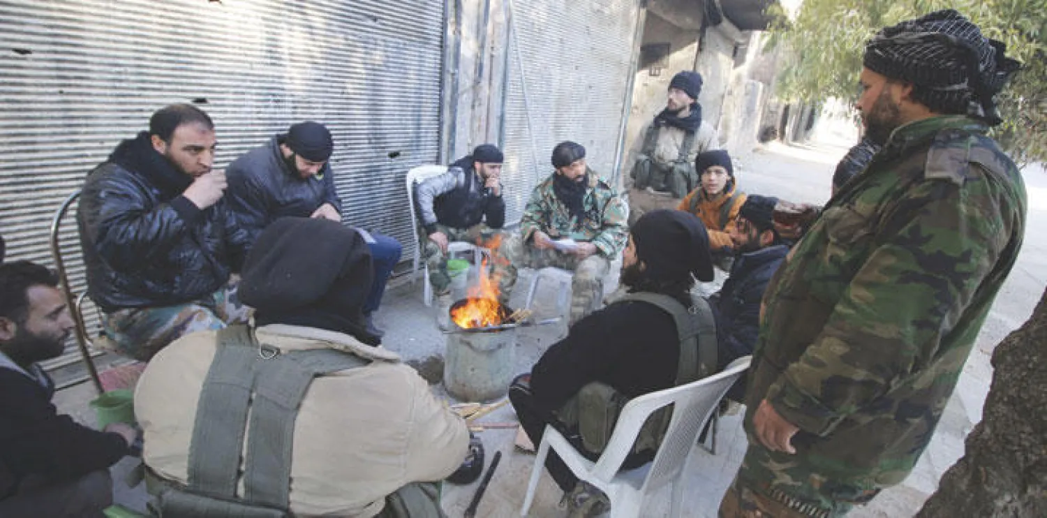 عناصر من الجبهة الشامية يلتفون حول موقد نار  طلبا للدفءفي أحد شوارع المدينة القديمة لحلب ({رويترز})