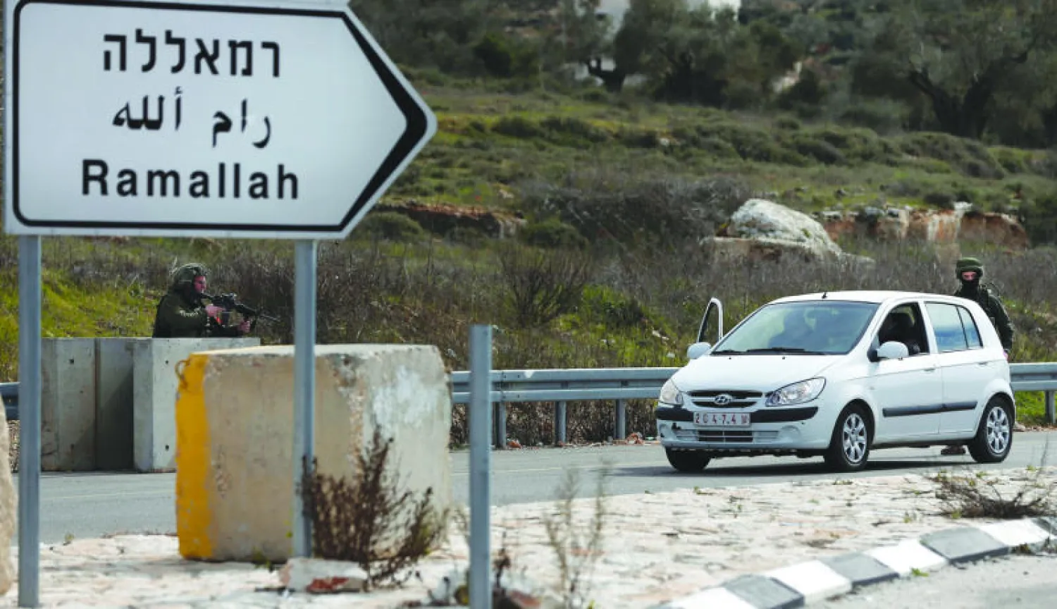 جنود إسرائيليون يفتشون سيارة فلسطينية شمال مدينة رام الله أمس (أ.ف.ب)