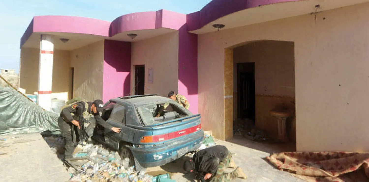 عناصر أمن عراقيون يعاينون سيارة خلال عملية لتطهير شرق الرمادي من مسلحي «داعش» أول من أمس (أ.ف.ب)