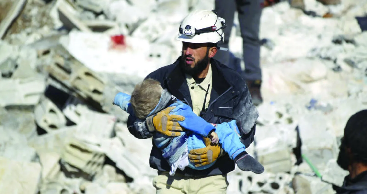 صورة تعود إلى يناير الماضي لعامل إنقاذ يحمل طفلا قتيلا إثر غارة روسية على معرة النعمان (رويترز)