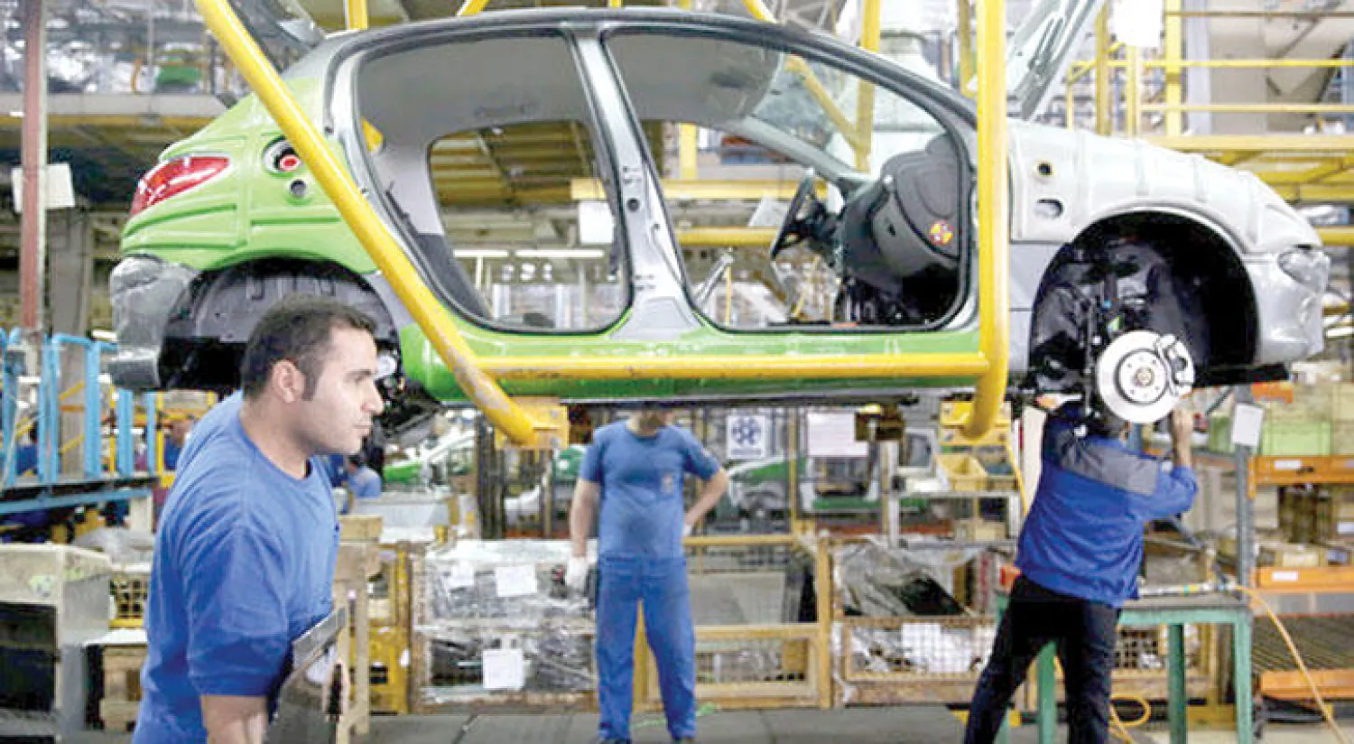 عاملون بأحد مصانع تجميع السيارات في مدينة خوردو الإيرانية (أ.ب)