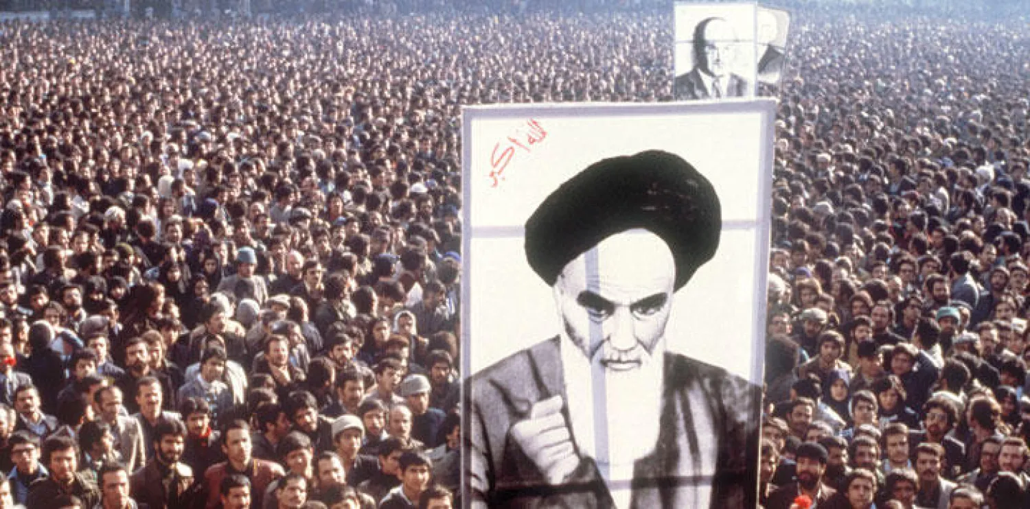 إيرانيون يرفعون صورة الخميني عشية وصوله من باريس إلى طهران في 1979 (غيتي)