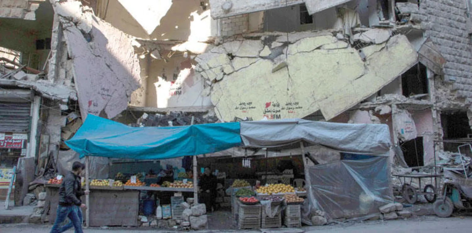 شاب من سكان مدينة حلب التي تتعرض لقصف يومي من الطيران الروسي يعبر سوق الخضار والأبنية التي تعرضت للدمار (أ.ف.ب)