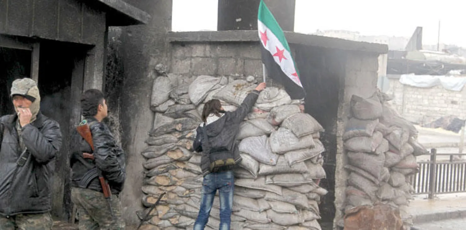 أحد الثوار يرفع علم المعارضة السورية فوق نقطة تفتيش خاضعة للجيش الحر في حلب (رويترز)