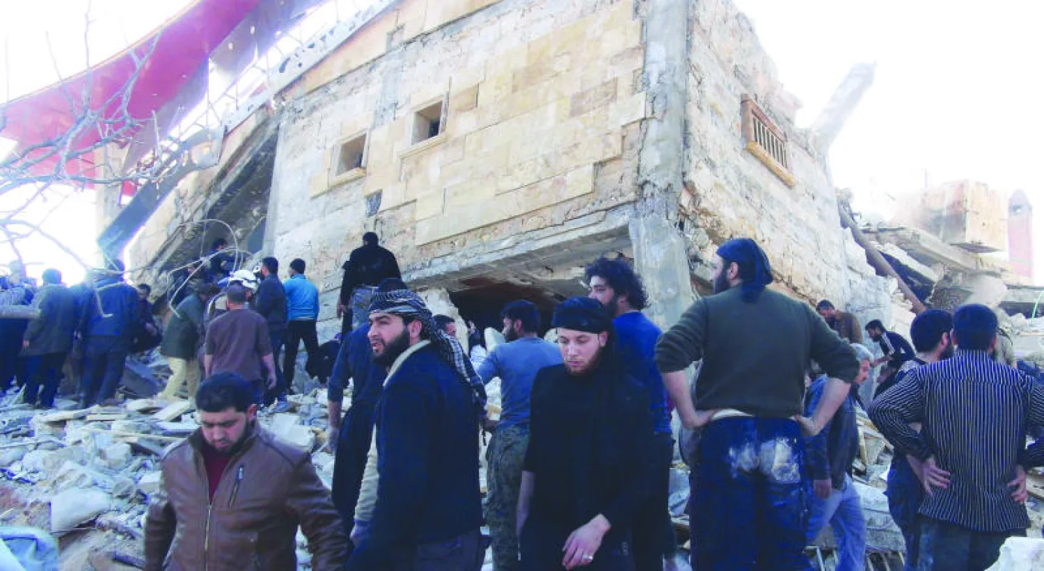 سكان من بلدة معرة النعمان بريف إدلب شمال سوريا تجمعوا حول ركام مستشفى استهدفه الطيران الروسي أمس (أ.ف.ب)