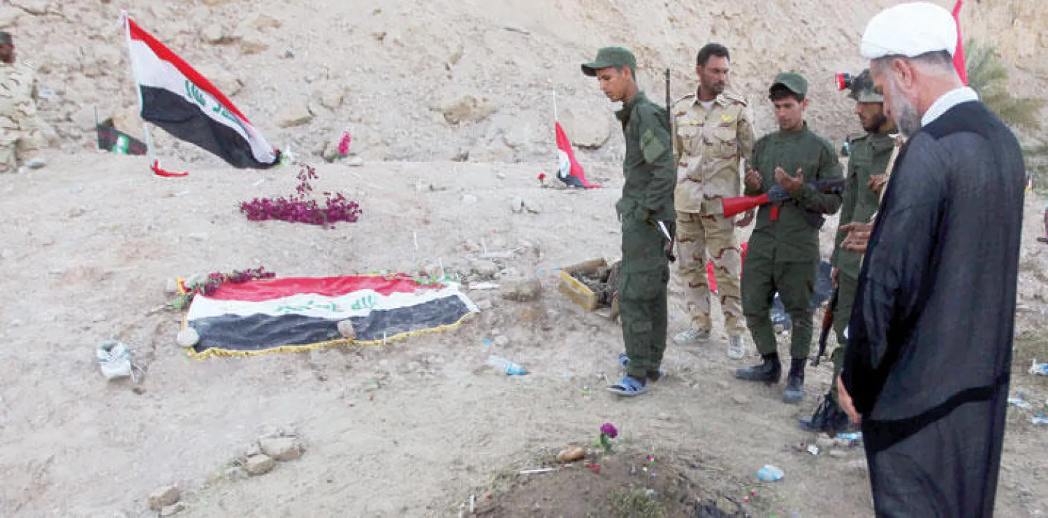 عناصر من ميليشيا {الحشد الشعبي} يقرأون الفاتحة في موقع مجزرة «سبايكر» التي قتل فيها مئات طلاب القوة الجوية (أ.ف.ب)