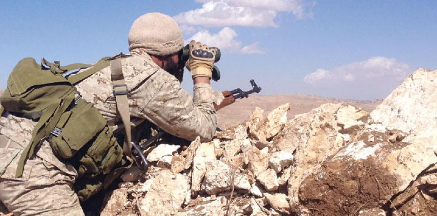 عنصر من ميليشيا حزب الله ينظر من خلال منظار في منطقة ام خورج بالقرب من الحدود السورية أمس (غيتي)