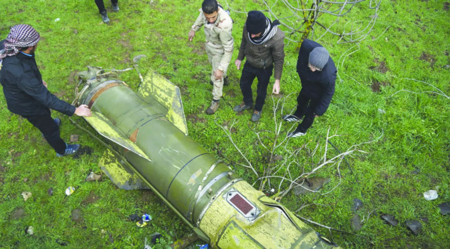 مقاتل من المعارضة السورية يتفحص قذيفة سقطت شمال ريف درعا والقنيطرة أمس (رويترز)