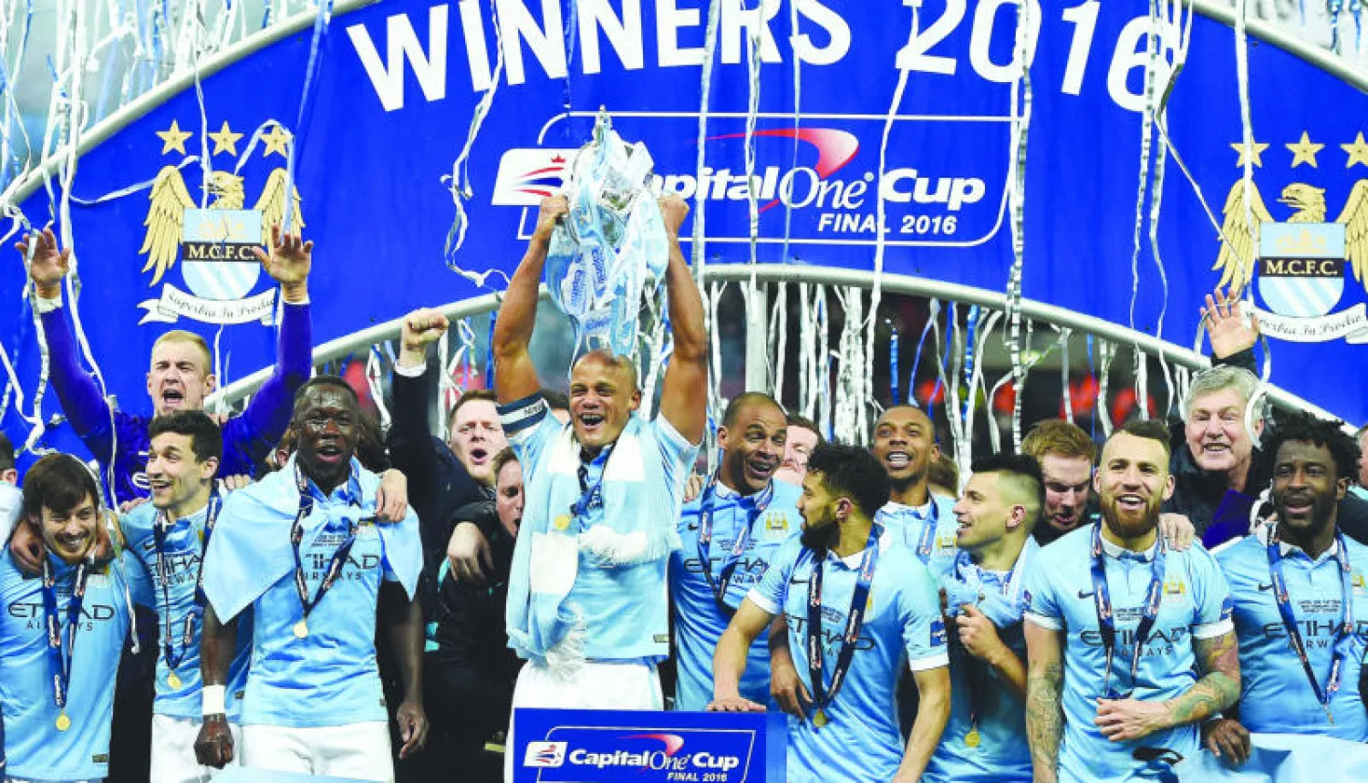 كامباني يحمل الكأس وسط احتفالات لاعبي سيتي بلقب رابطة المحترفين (إ.ب.أ)
