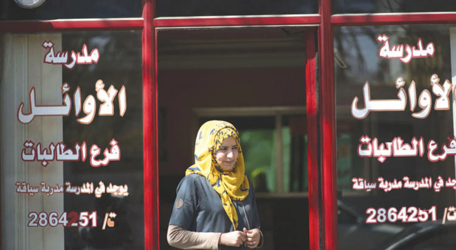 فلسطينية أمام مدرسة لتعليم قيادة السيارات في غزة (أ.ف.ب)