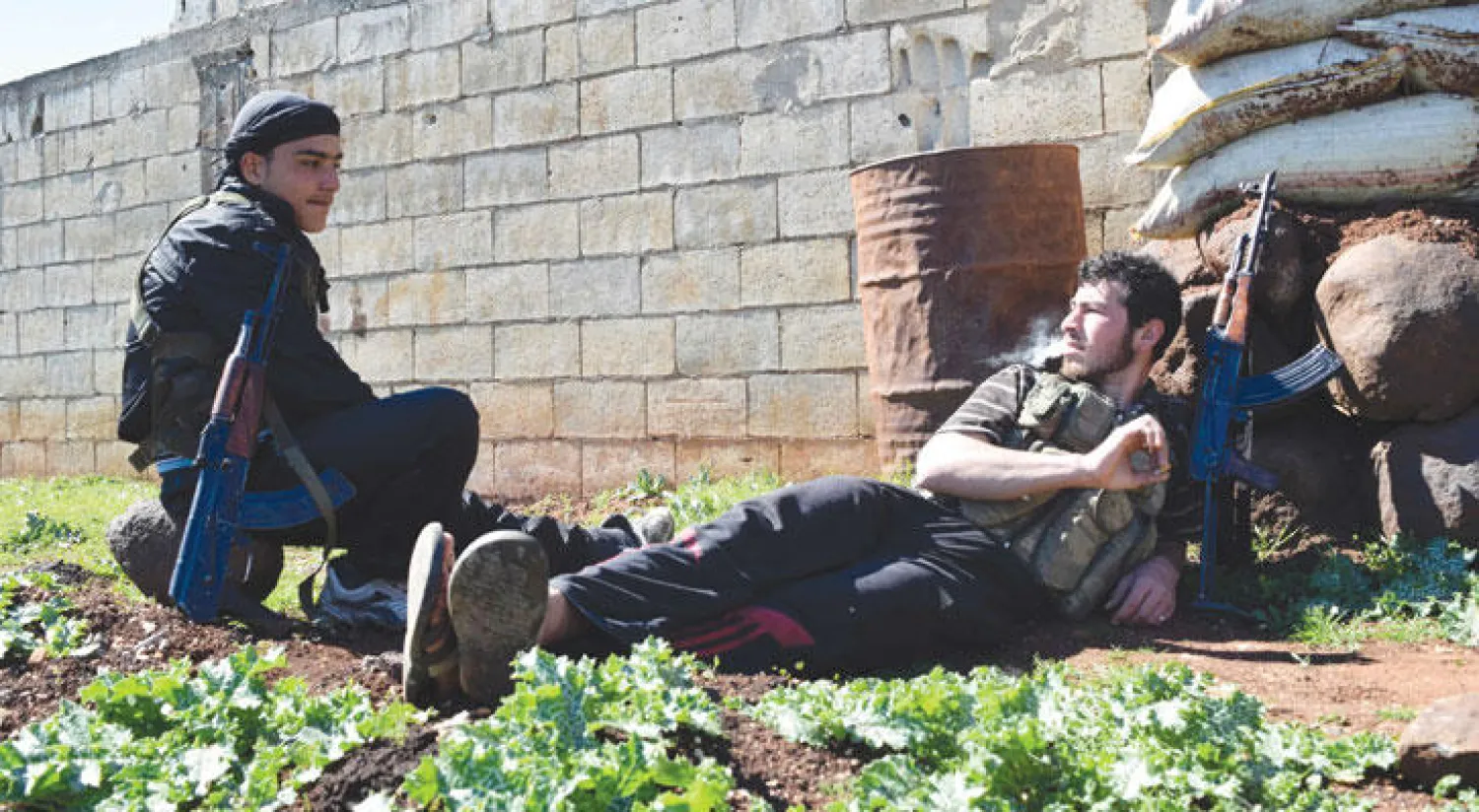 مقاتلان من الفصائل السورية المعارضة في استراحة محارب بريف حمص وسط سوريا في اليوم الرابع للهدنة (أ.ف.ب)
