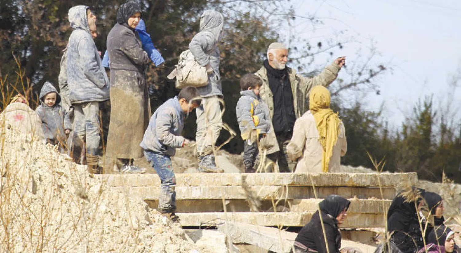 نازحون سوريون ينتظرون عند بلدة خربة الجوز لعبور الحدود التركية، الأسبوع الماضي، هربا من المعارك التي يشنها النظام في ريف اللاذقية (رويترز)