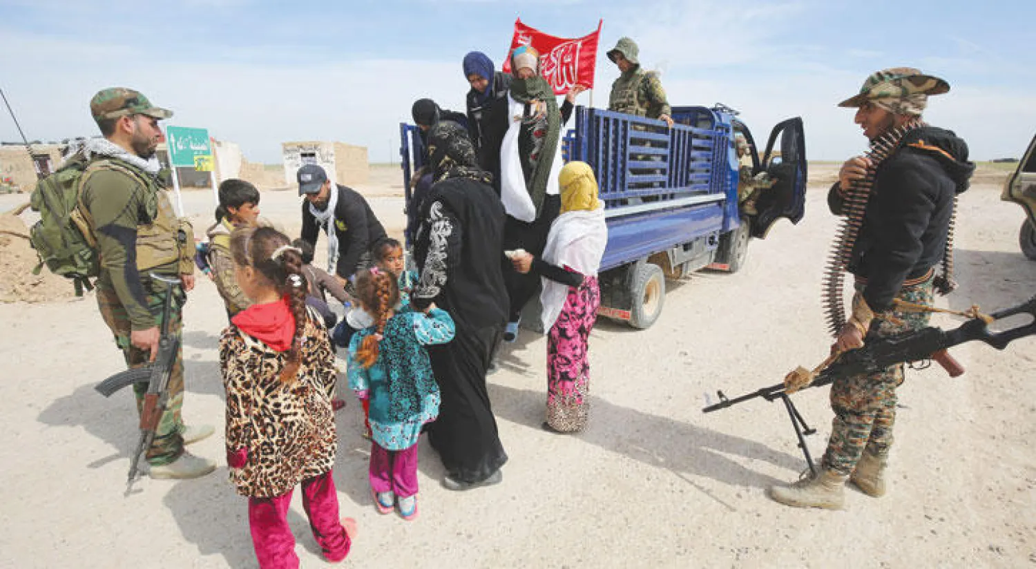 عناصر من قوات الأمن العراقية يساعدون عائلات من سامراء تركت المدينة هربا من تنظيم داعش (أ.ف.ب)