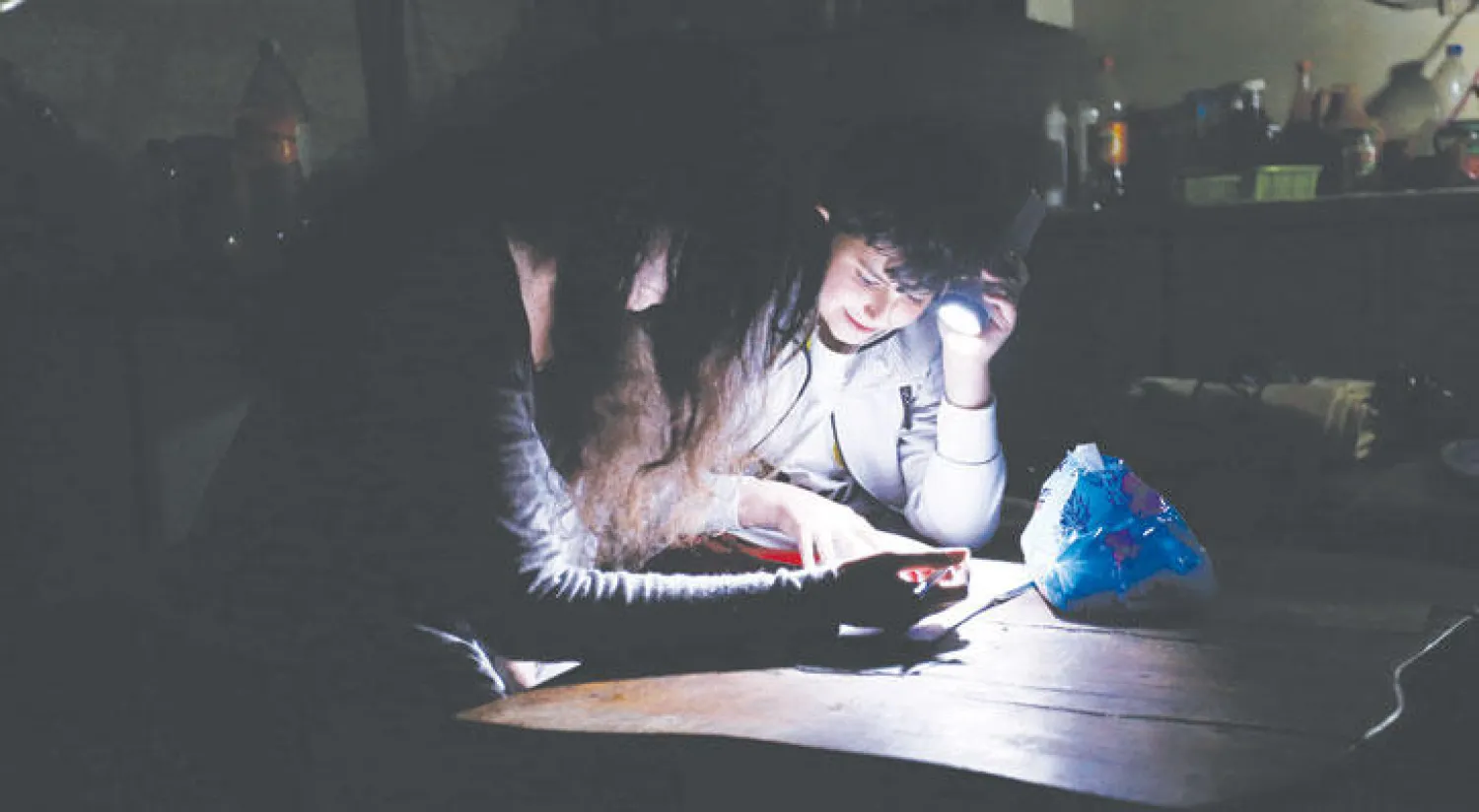 أطفال سوريون يؤدون واجباتهم المدرسية على ضوء بطارية بعد انقطاع الكهرباء وتعطل خدمة الإنترنت جزئيًا عن كامل سوريا أمس (إ.ب.أ)