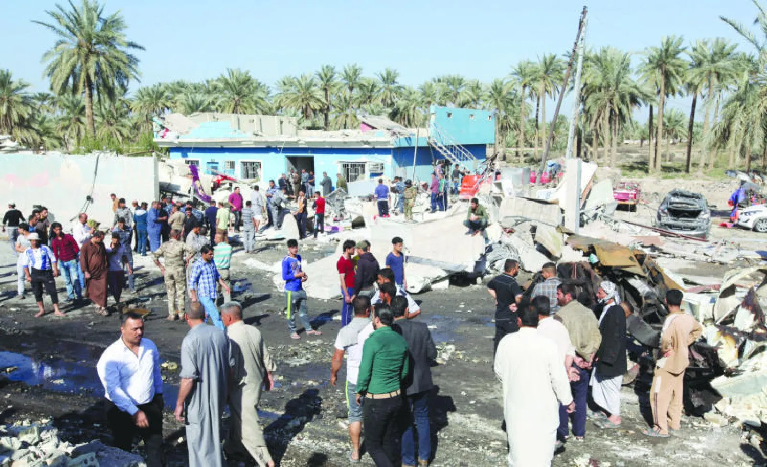 عراقيون في موقع الانفجار الذي استهدف نقطة تفتيش في مدينة الحلة أمس (رويترز)