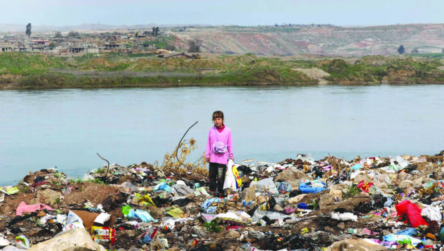 صبية عراقية تنبش بين أكوام القمامة بحثاً عن أي شيء قابل للاستهلاك بجانب نهر دجلة قرب مدينة الموصل (أ.ف.ب)