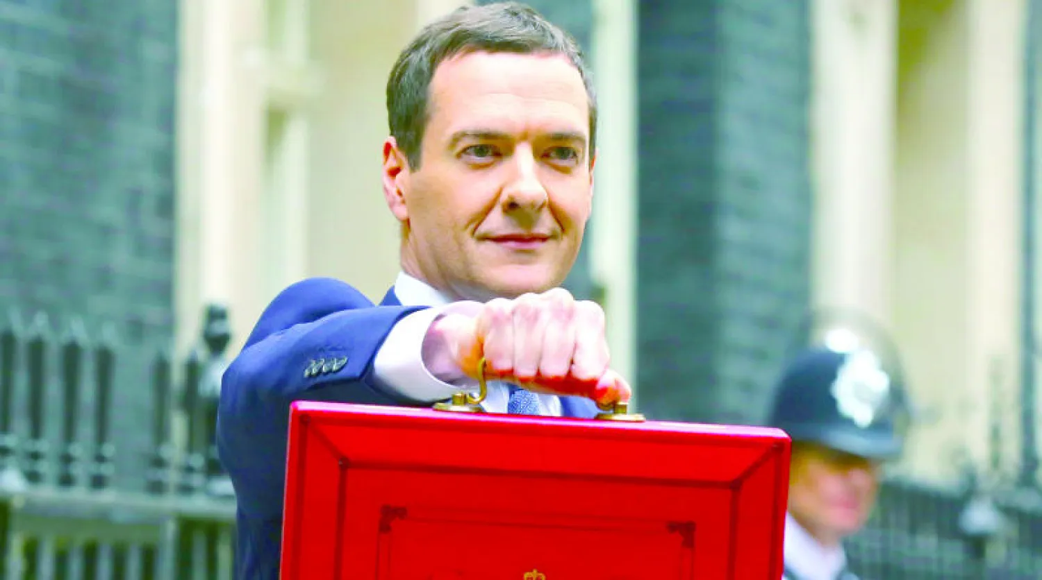 وزير المالية البريطاني جورج أوزبورن حاملا ميزانية العام الماضي قبل عرضها على مجلس العموم (رويترز)