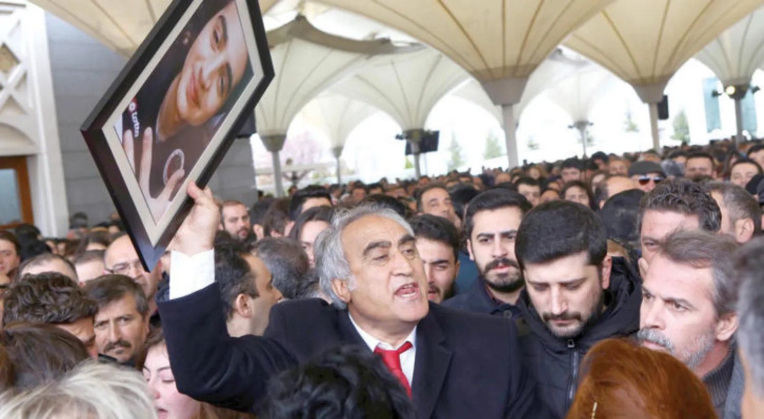 والد الشاب الفين بورغا أرسلان الذي لقي حتفه في تفجير أنقرة الإرهابي  يحمل صورته أثناء تشييع جثمانه بين أقاربه أمس (أ.ف.ب)