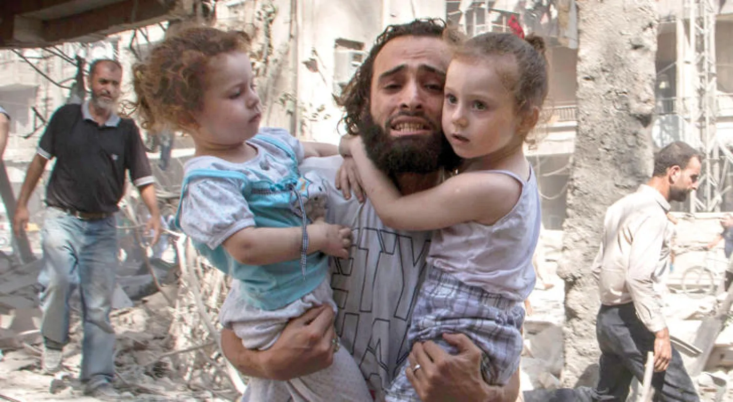 سوري يحاول الفرار مع ابنتيه من القصف شمال حلب (غيتي)