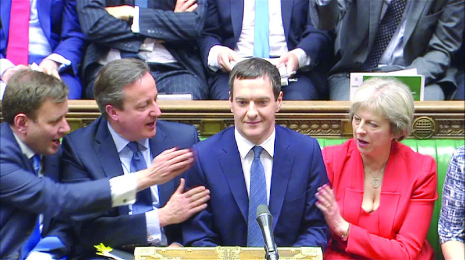 وزير الخزانة البريطاني جورج أوزبورن بعد تقديمه خطة  الميزانية التي قدمها بينما يحيه رئيس الوزراء ديفيد كاميرون (وسط)  أمس (رويترز)