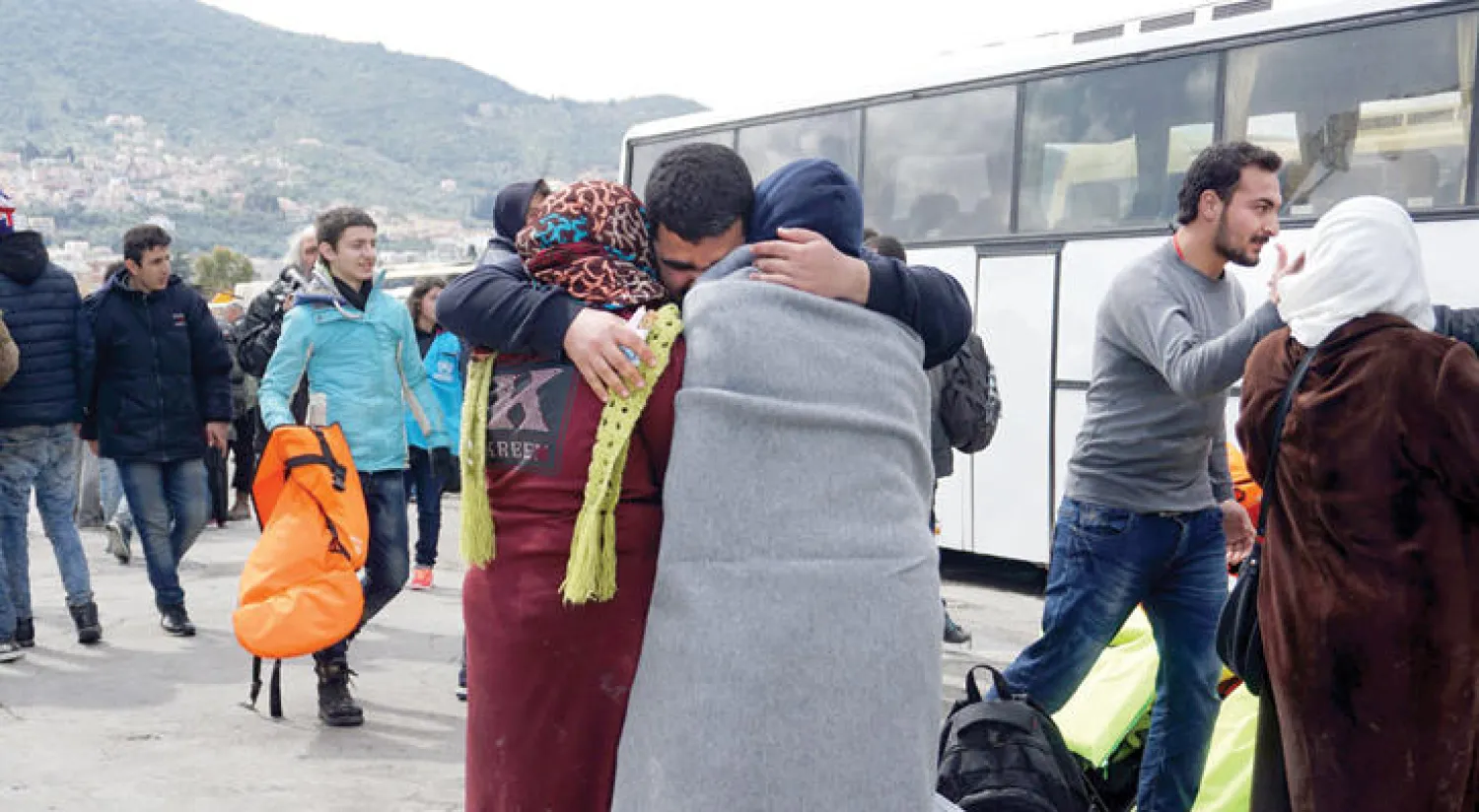 مهاجرون يعانق بعضهم بعضا بعد وصولهم إلى جزيرة  ميتلين اليونانية أمس (أ.ف.ب)