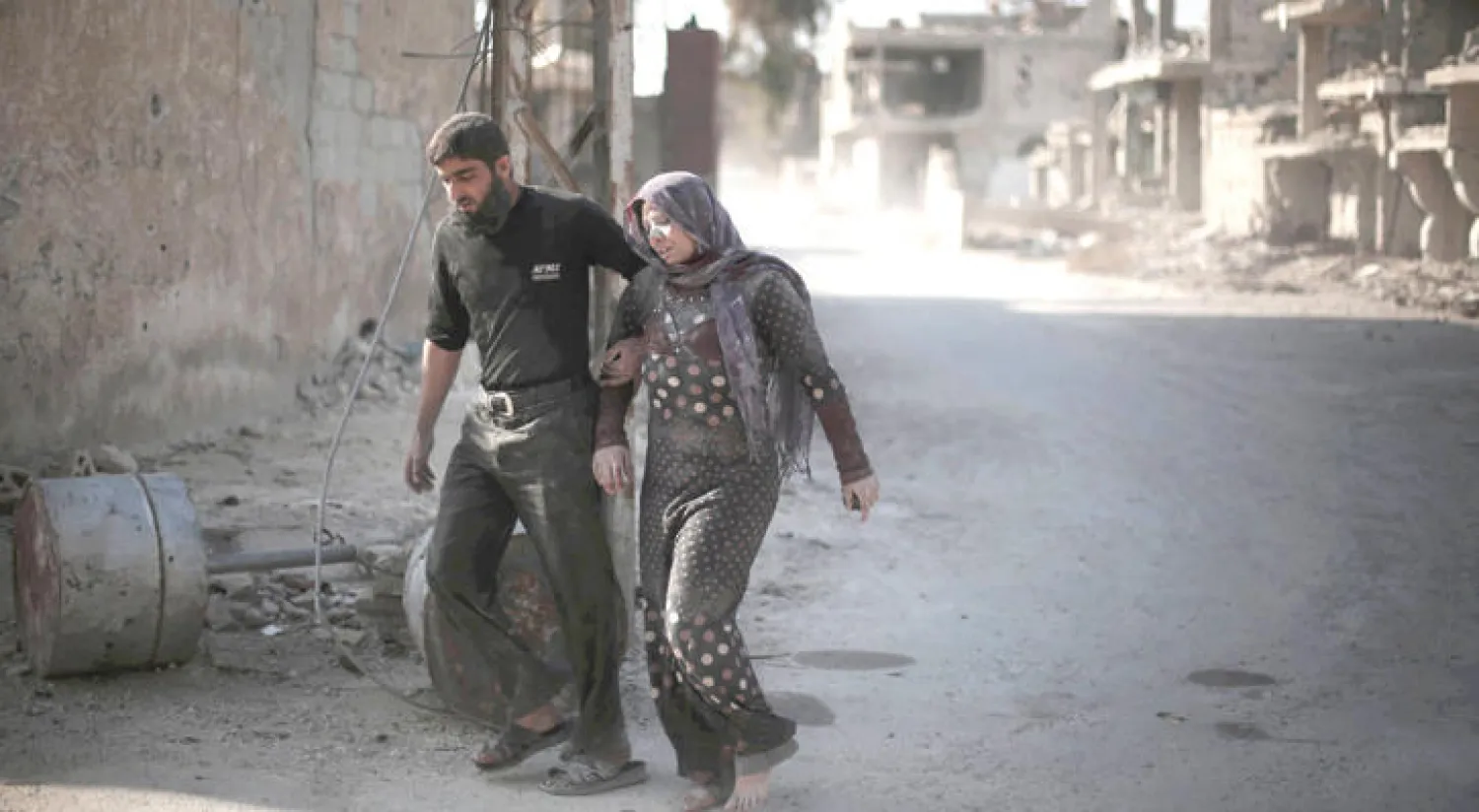 سوري وزوجته المصابة يتجهان إلى مكان آمن بعد القصف الذي تعرضت له مدينة الغوطة (أ.ف.ب)