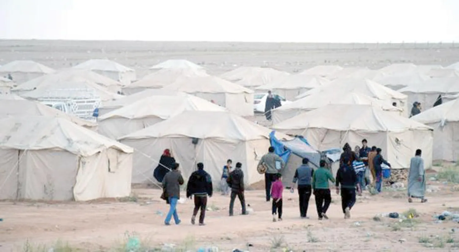 عراقيون يسيرون في مخيم «وفا» للنازحين غرب الرمادي أمس (إ.ب.أ)
