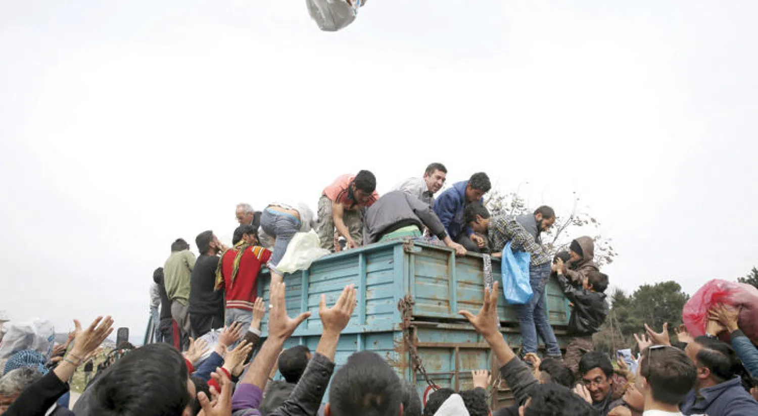 مهاجرون وطالبو لجوء يتسلمون مساعدات إنسانية في إيدوميني القريبة من الحدود اليونانية-المقدونية أمس (رويترز)