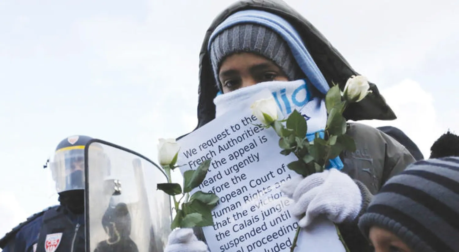 أطفال يقدمون ورودًا لرجال الأمن الفرنسي خلال مظاهرة سلمية في كاليه في 7 مارس الماضي (واشنطن بوست)