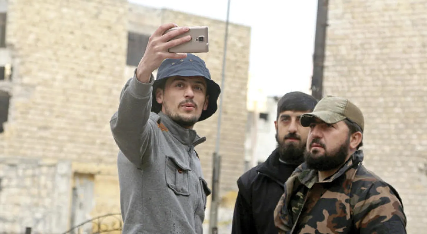 شاب سوري يلتقط صورة سيلفي مع مقاتلين من المعارضة في حي صلاح الدين بمدينة حلب شمال سوريا (رويترز)