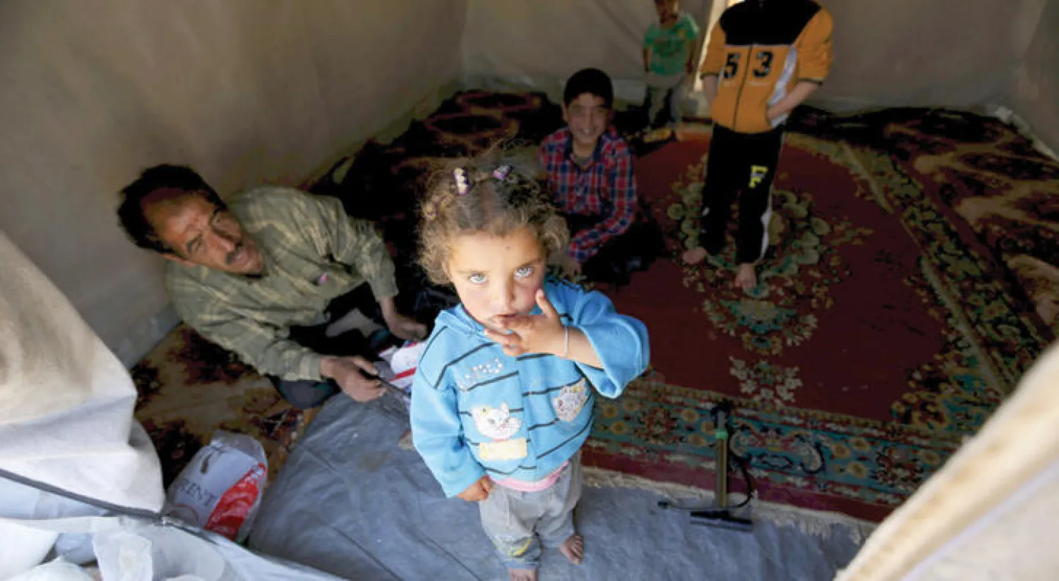 طفلة سورية مع أسرتها في إحدى الخيام بمعسكر اللاجئين في بلدة دانا جنوب إدلب (رويترز)