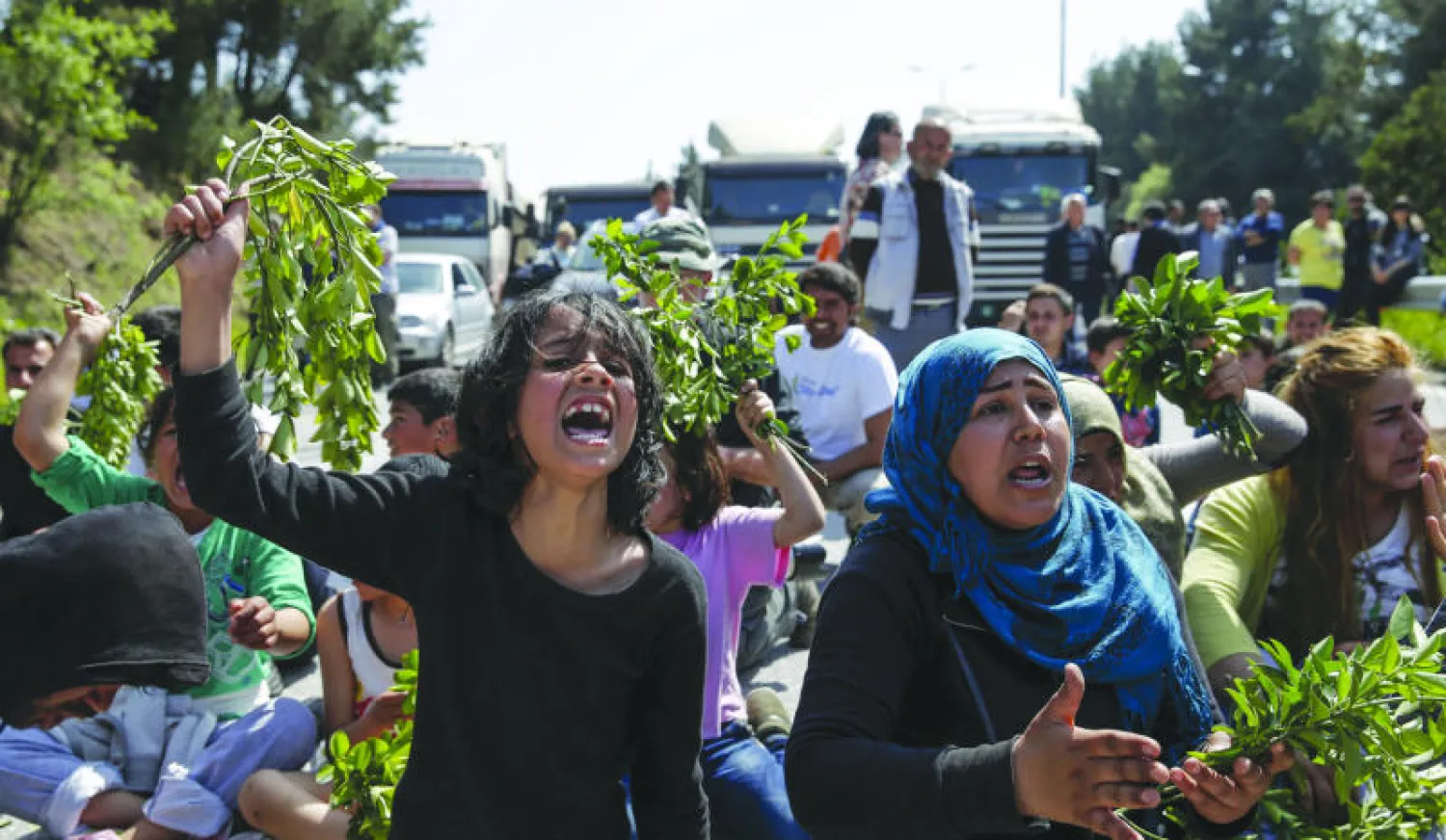 مهاجرون ولاجئون يرددون هتافات وهم يقطعون طريقا قرب الحدود اليونانية ــ المقدونية أمس (رويترز)