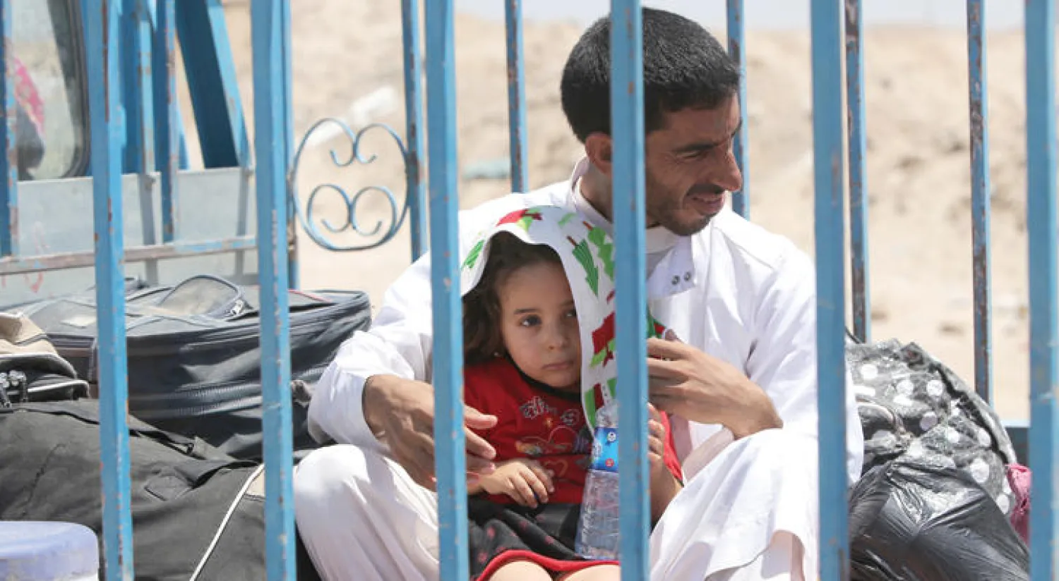 عراقي مع طفلته متجها غرب الفلوجة فارا من القتال الدائر فيها (أ.ف.ب)