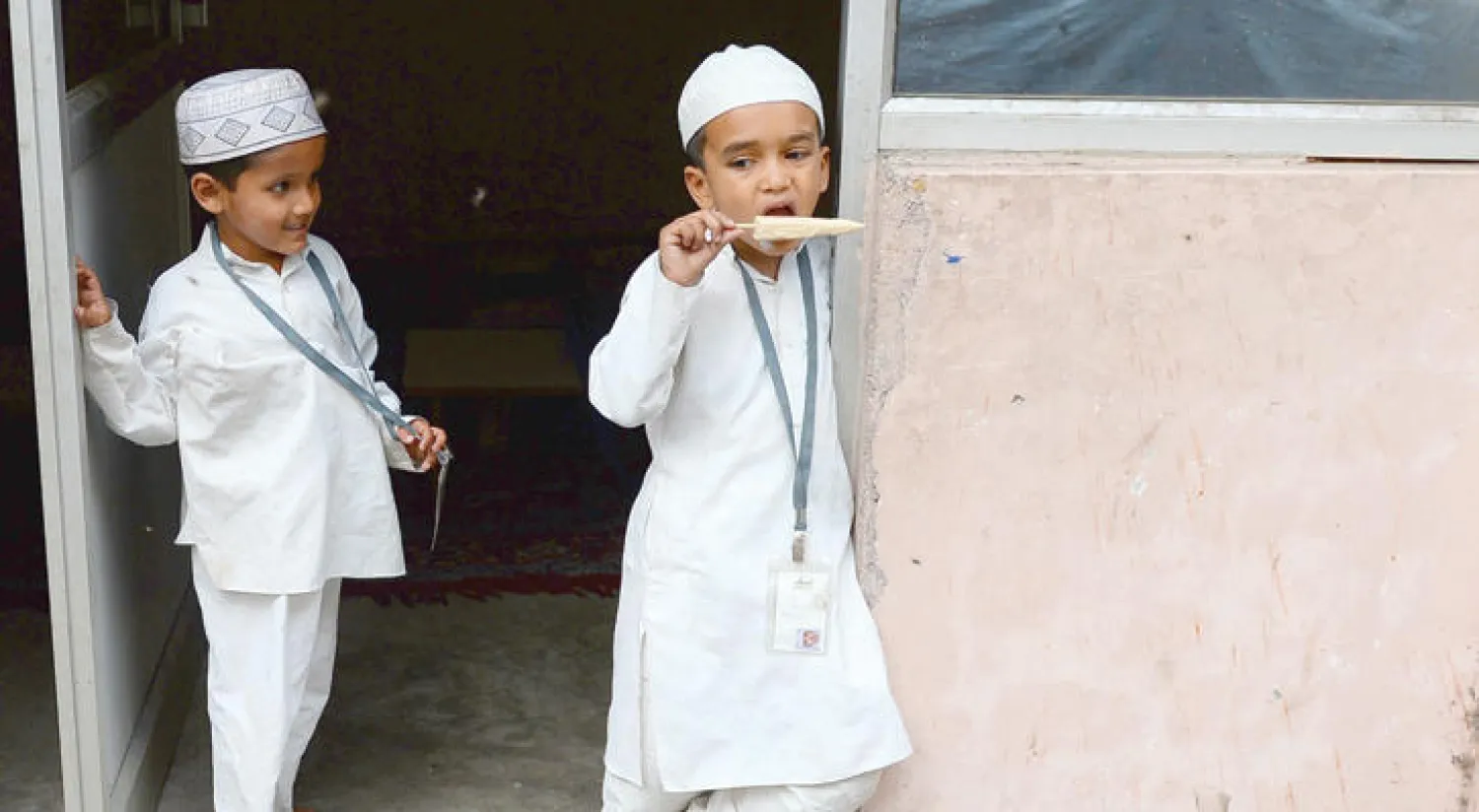 طفلان يلهوان عند مدخل مدرسة مسلمة في نيودلهي في 31 مارس الماضي (أ.ف.ب)