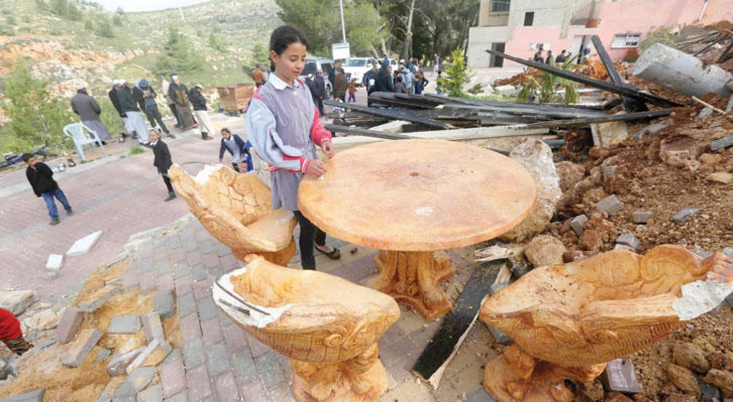 فلسطينيون يتجمعون أمام أنقاض ملعب للأطفال  كان بني بتمويل من بلجيكا جنوب من مدينة نابلس بالضفة الغربية بعد أن تم هدمه من قبل السلطات الإسرائيلية أمس (أ.ف.ب)