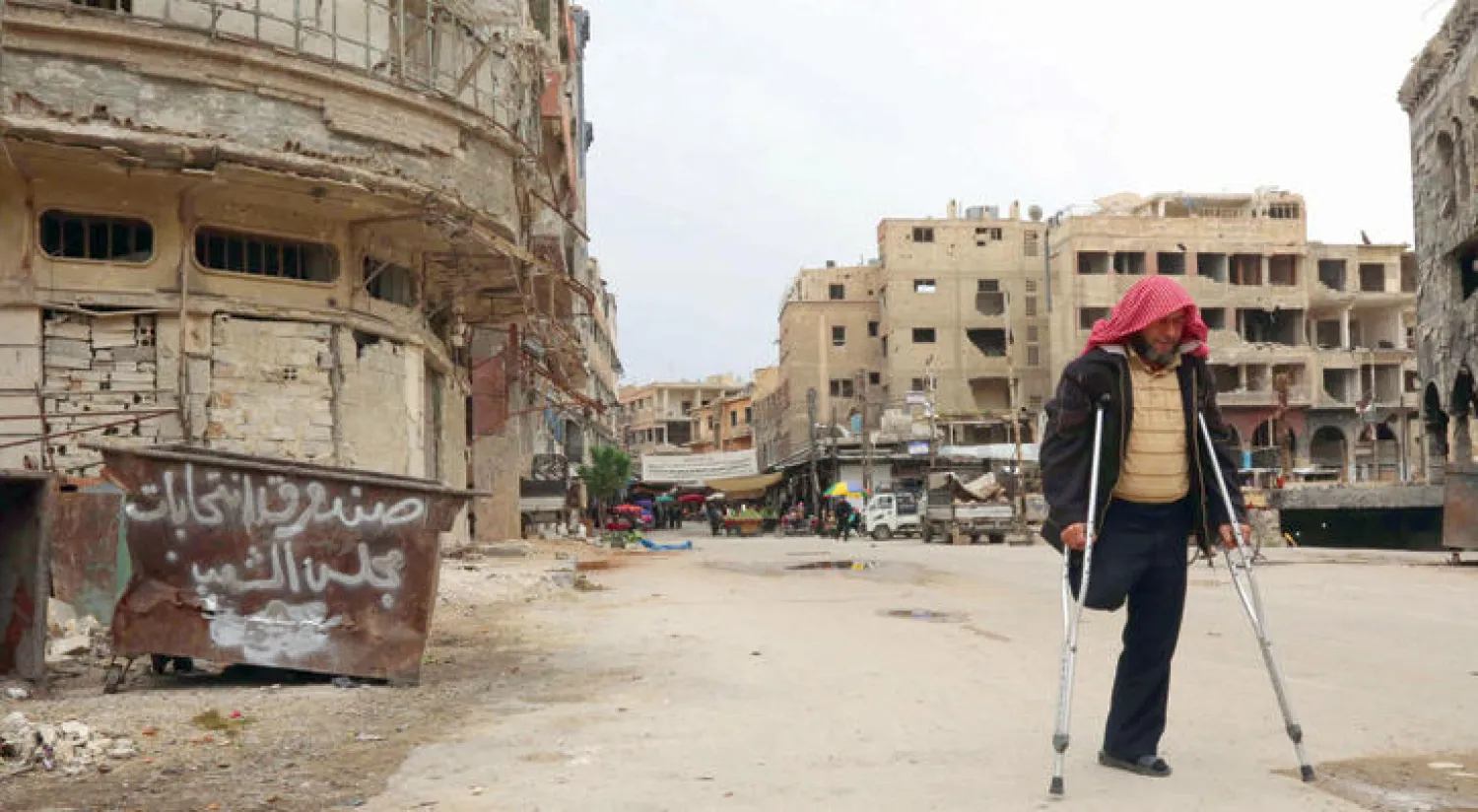 رجل سوري مصاب في قدمه.. يعبر صندوق قمامة كتب عليه «صندوق انتخابات مجلس الشعب» في إشارة إلى الانتخابات التي جرت أمس (إ.ف.ب)