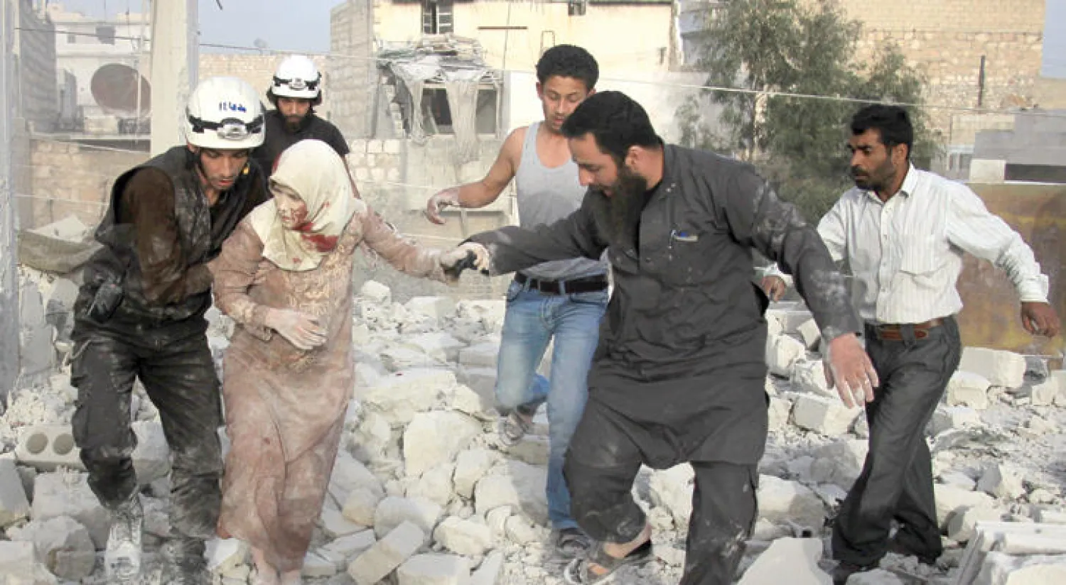 مسعفون ومدنيون يخرجون إمراة من تحت الأنقاض بعد استهداف منزلها من قبل طائرات النظام شمال مدينه حلب (أ.ف.ب)