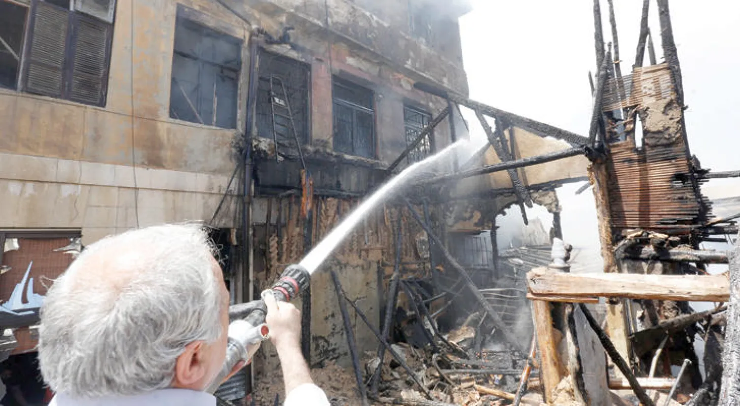 اطفائي يحاول اخماد النيران التي اندلعت في إحدى أهم الأسواق التاريخية في دمشق القديمة أمس (أ.ف.ب)