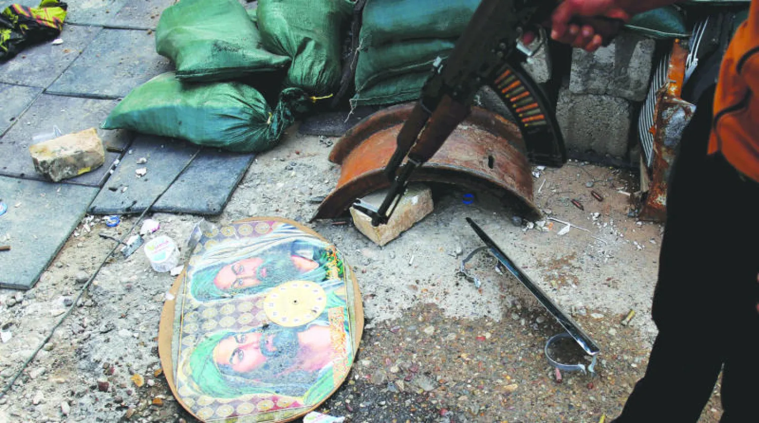 مسلح كردي يعاين ما تبقى من ميليشيات الحشد الشعبي بعد مواجهات بينها وبين قوات أخرى كردية بمنطقة طوزخورماتو (رويترز)