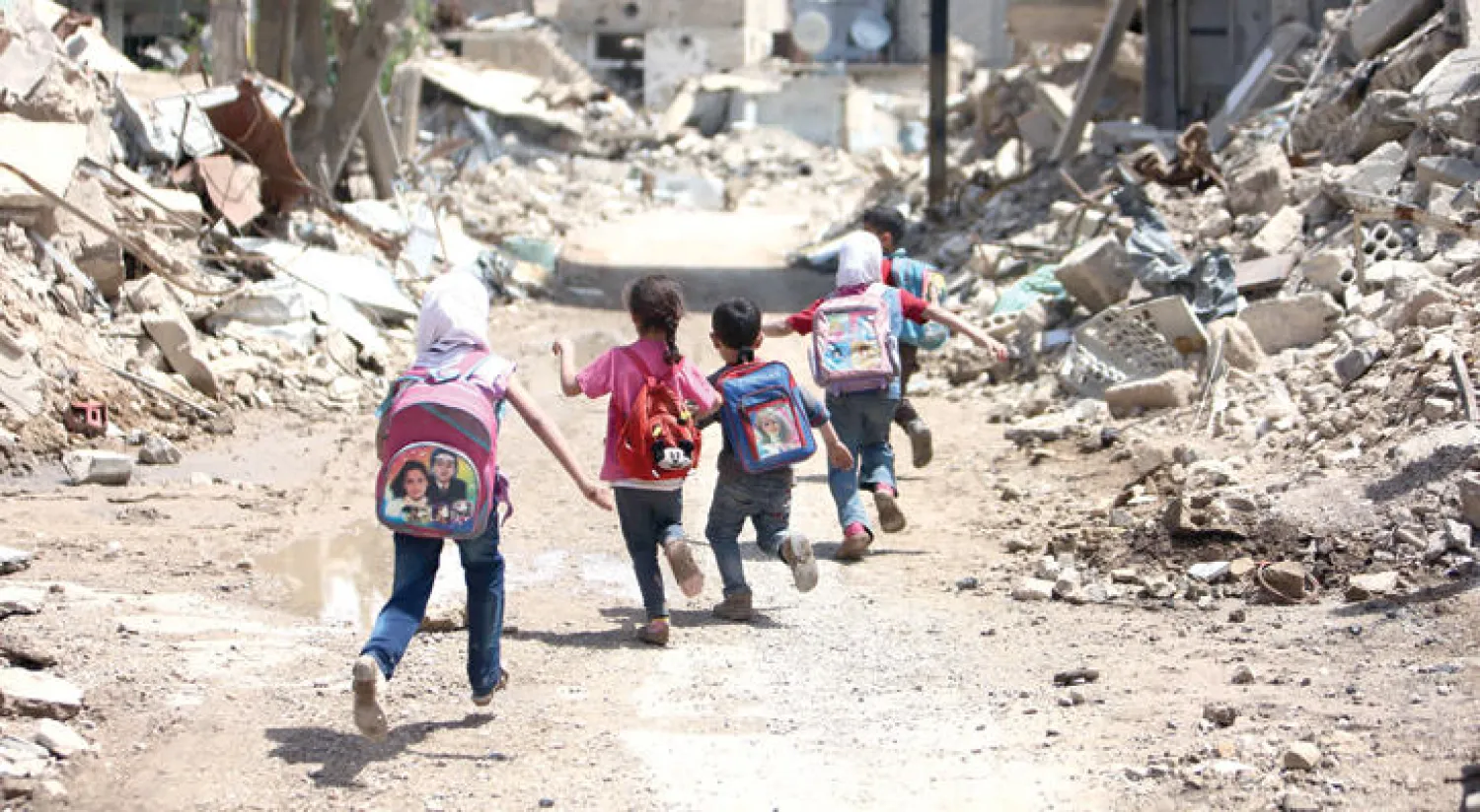 أطفال سوريون في طريقهم إلى المدرسة وسط أنقاض أحد الاحياء وسط دمشق (أ.ف.ب)