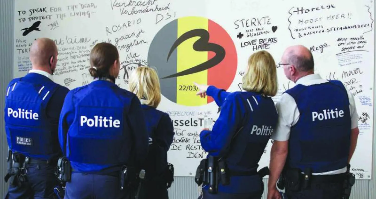 ضباط شرطة بلجيكيون يتابعون التعليقات الخاصة بضحايا تفجيرات مطار بروكسل عقب عودة العمل إلى صالة المسافرين (أ.ف.ب)