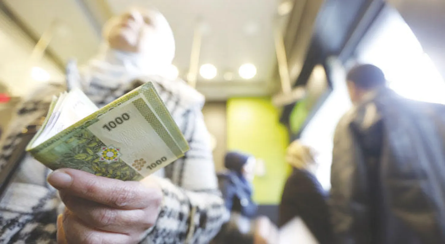 امرأة سورية تحمل أوراقًا من العملة السورية داخل محل صرافة في دمشق (رويترز)