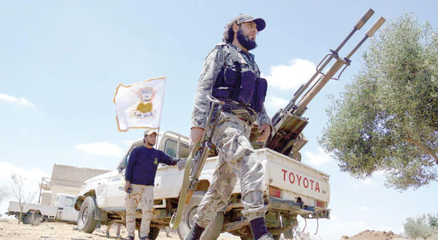 مقاتلان من مجموعة ألوية الفاروق بالقرب من سيارة تحمل مدفعاً مضاداً للطيران في إحدى قرى درعا (رويترز)