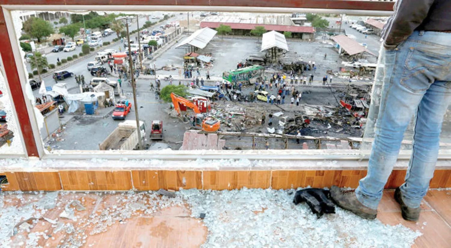 رجل يقف قرب نافذة محطمة يبدو من خلالها الاضرار التي اصابت محطة حافلات جبلة بريف اللاذقية بفعل التفجير الذي تبناه داعش اول من امس (رويترز)