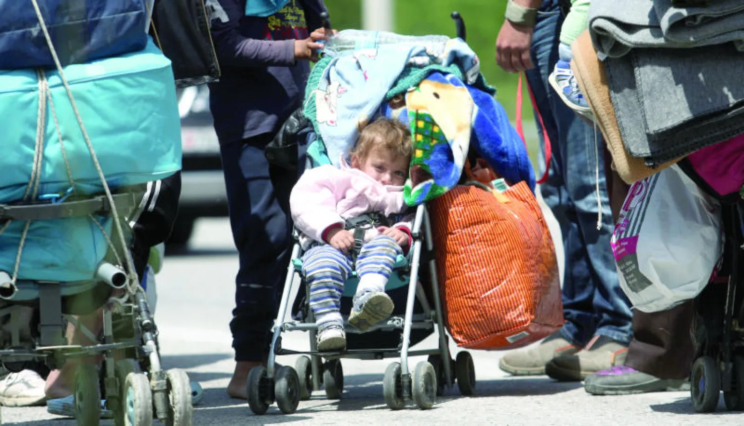 مهاجرون ولاجئون يحملون أمتعتهم استعدادا لمغادرة مخيم إيدوميني أمس (أ.ف.ب)