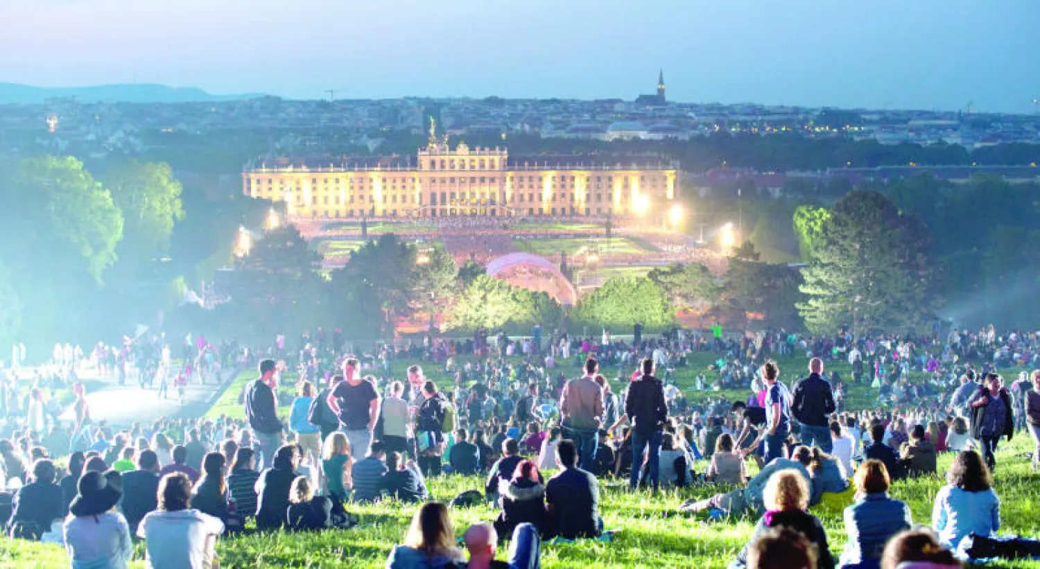 الجمهور يفترش الأرض لمشاهدة الحفل الموسيقي الذي أقامته فرقة «فيينا فيلهارمونيكا» بقصر الشونبرون في العاصمة النمساوية (إ.ب.أ)