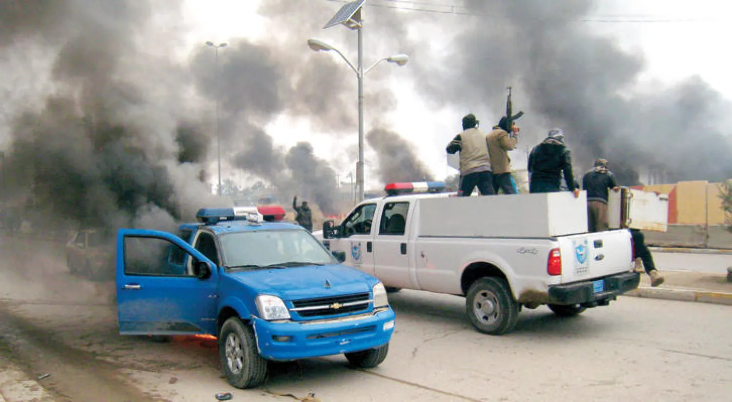 عناصر من تنظيم داعش يستخدمون سيارة خاصة بالشرطة العراقية استولوا عليها في مدينة الفلوجة بعد إحراق مقر الشرطة هناك (أ.ب)