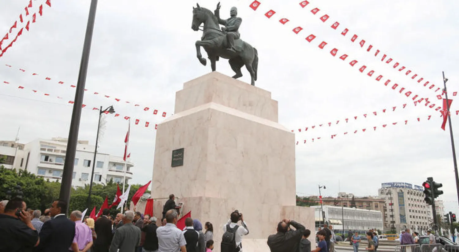 تونسيون يقفون أمام نصب بورقيبة التذكاري في الشارع الذي يحمل اسمه وسط العاصمة التونسية أمس (رويترز)